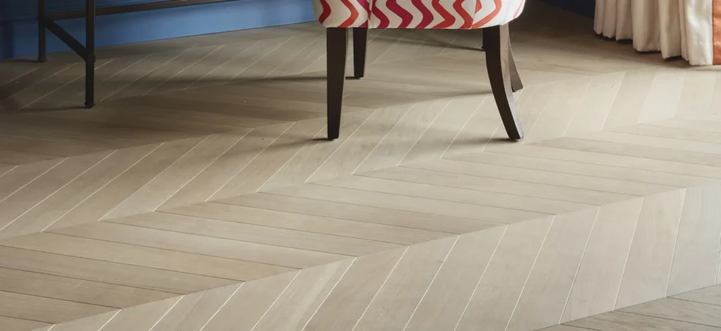 A close-up of light-colored chevron wood flooring