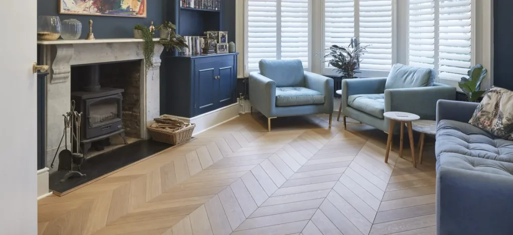A living room featuring light-colored chevron wood flooring