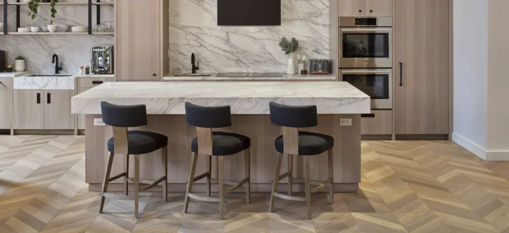 A modern kitchen featuring light-toned herringbone wood flooring