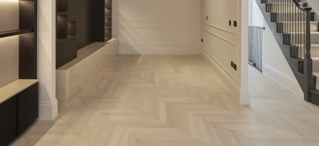 A spacious hallway featuring light-colored chevron wood flooring